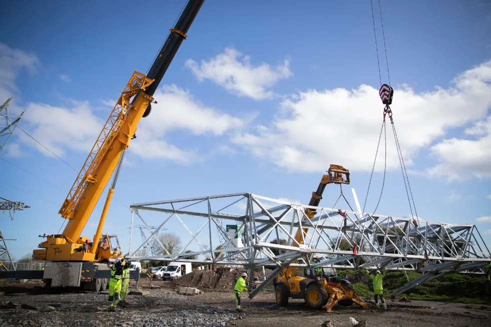 Tusker mobile crane lifting steel tower frame on site