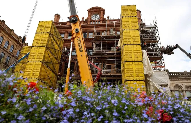 Tusker crane lifting yellow containers during historic building renovation