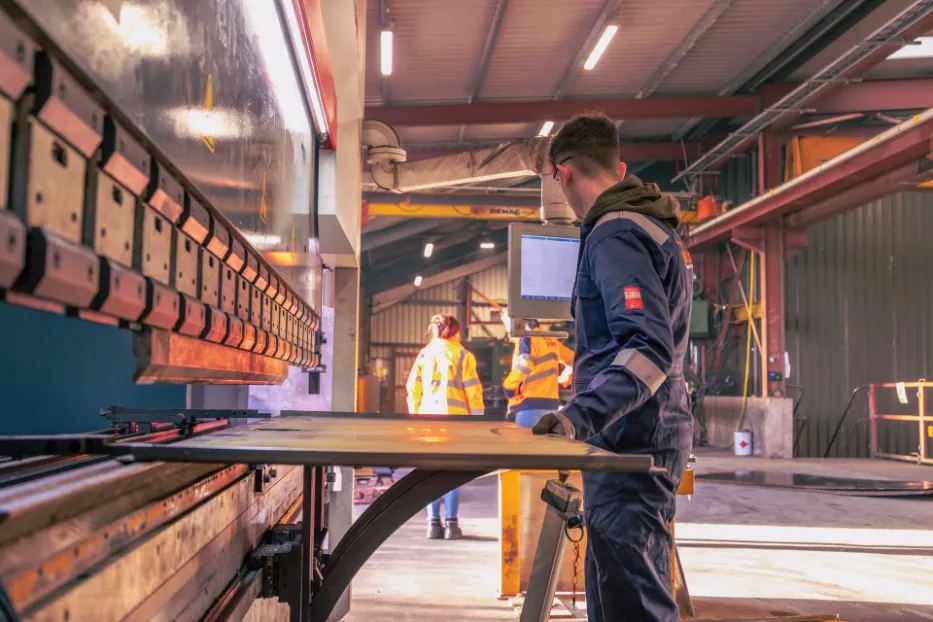 Worker operating CNC press brake for steel fabrication